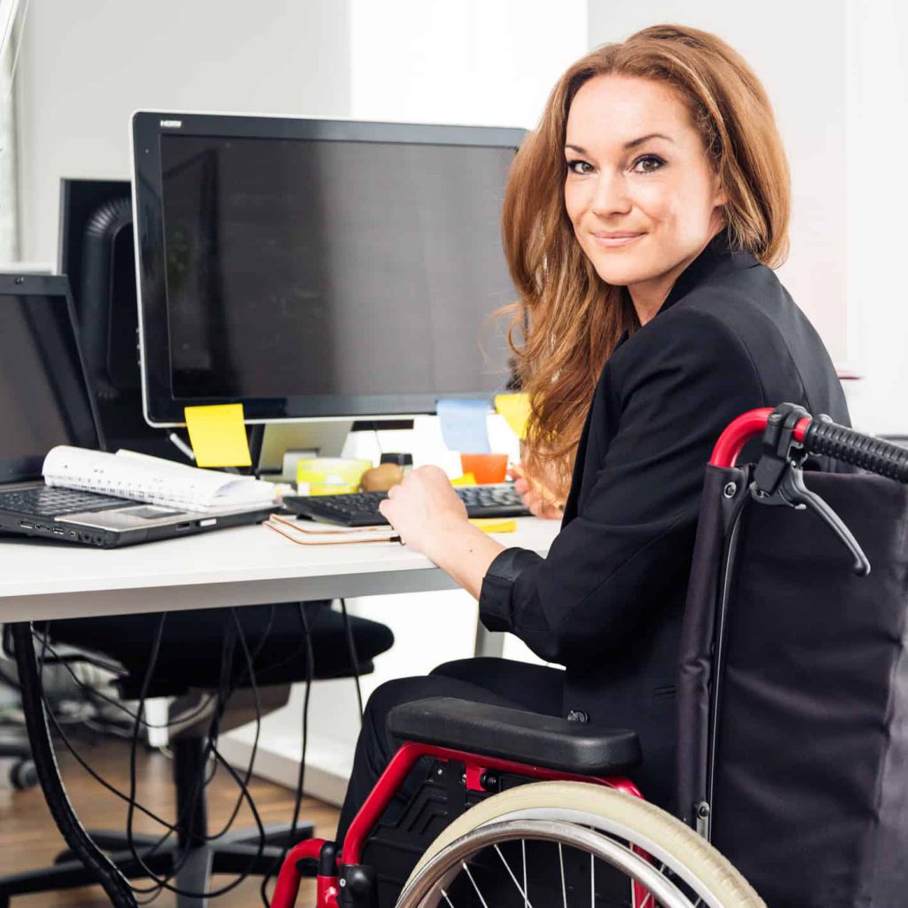 a woman sitting in a wheelchair is working in a modern office